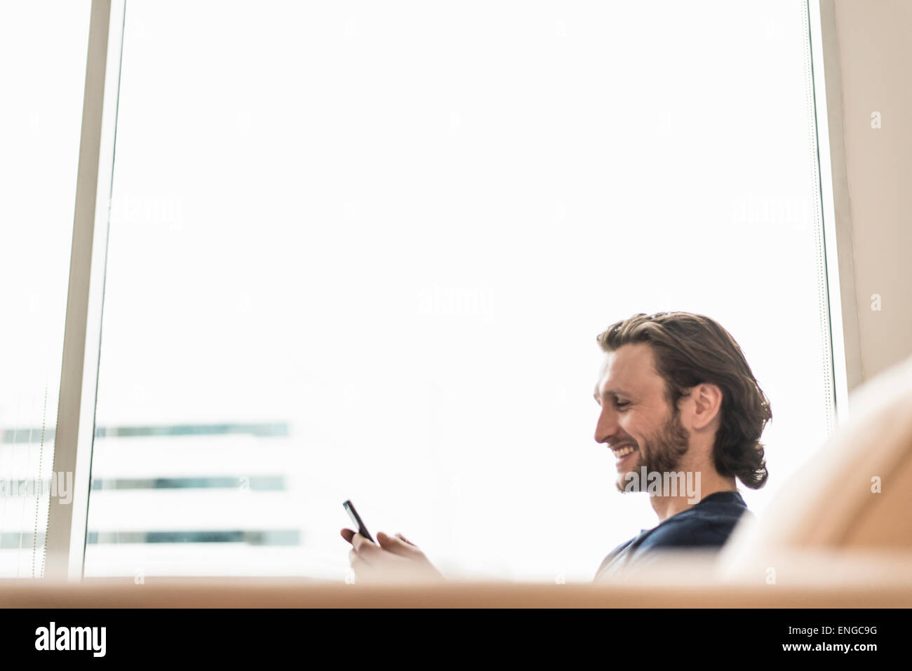 Ein Mann sitzt sein Smartphone überprüfen und lachen. Stockfoto
