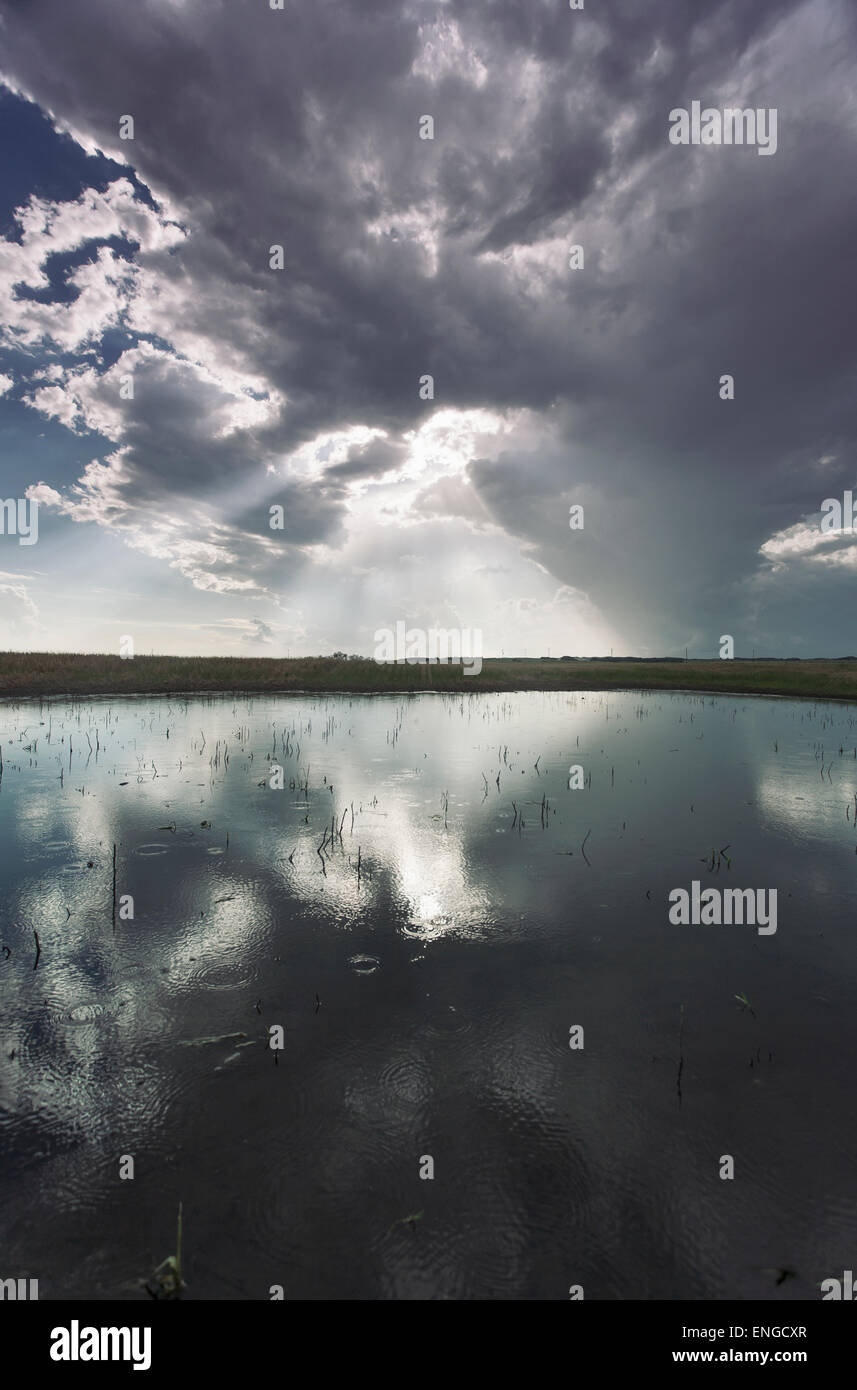 Die Reflexion von einem dramatischen Himmel in die flache Oberfläche eines Sees. Stockfoto