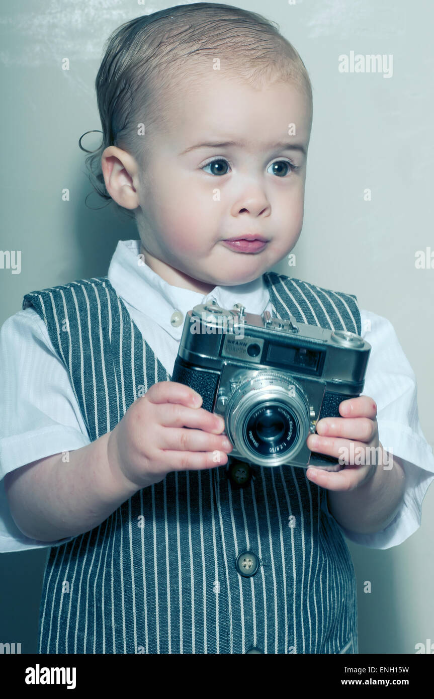 Altmodische Stil Porträt von niedlichen kaukasischen Kleinkind in eine Weste, eine Kamera zu halten Stockfoto