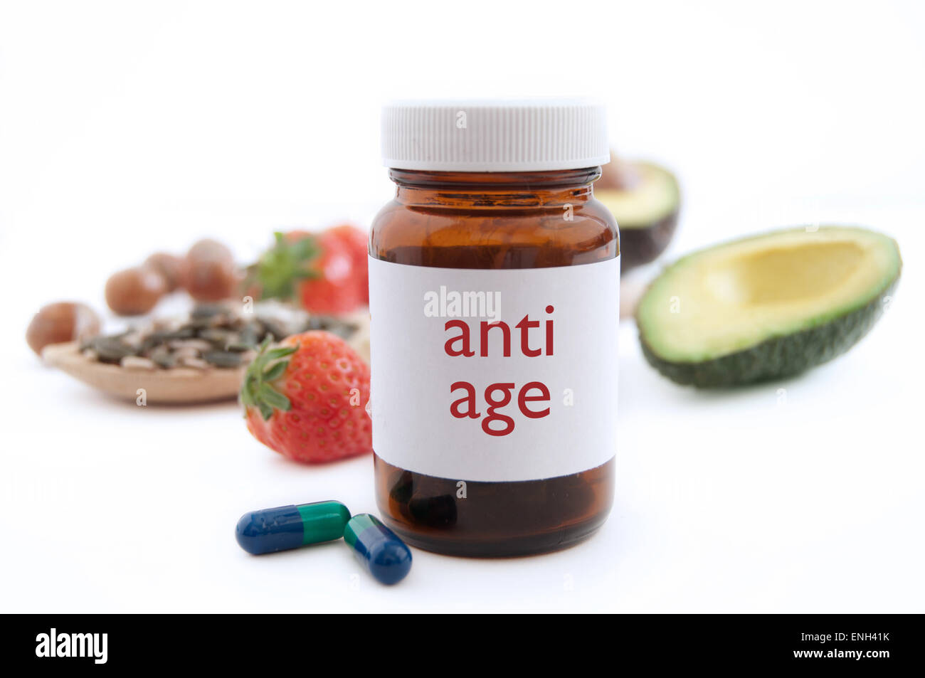 Medizin-Glas mit anti-aging-Pillen umgeben von nahrhaften Superfoods wie Avocado, Kürbis Samen und Beeren Stockfoto