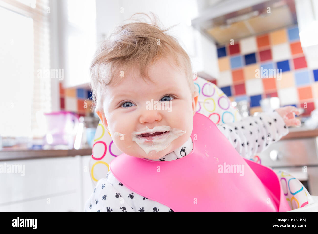 Sechs Monate altes Babymädchen mit chaotisch Gesicht nach der Fütterung auf Brei Stockfoto