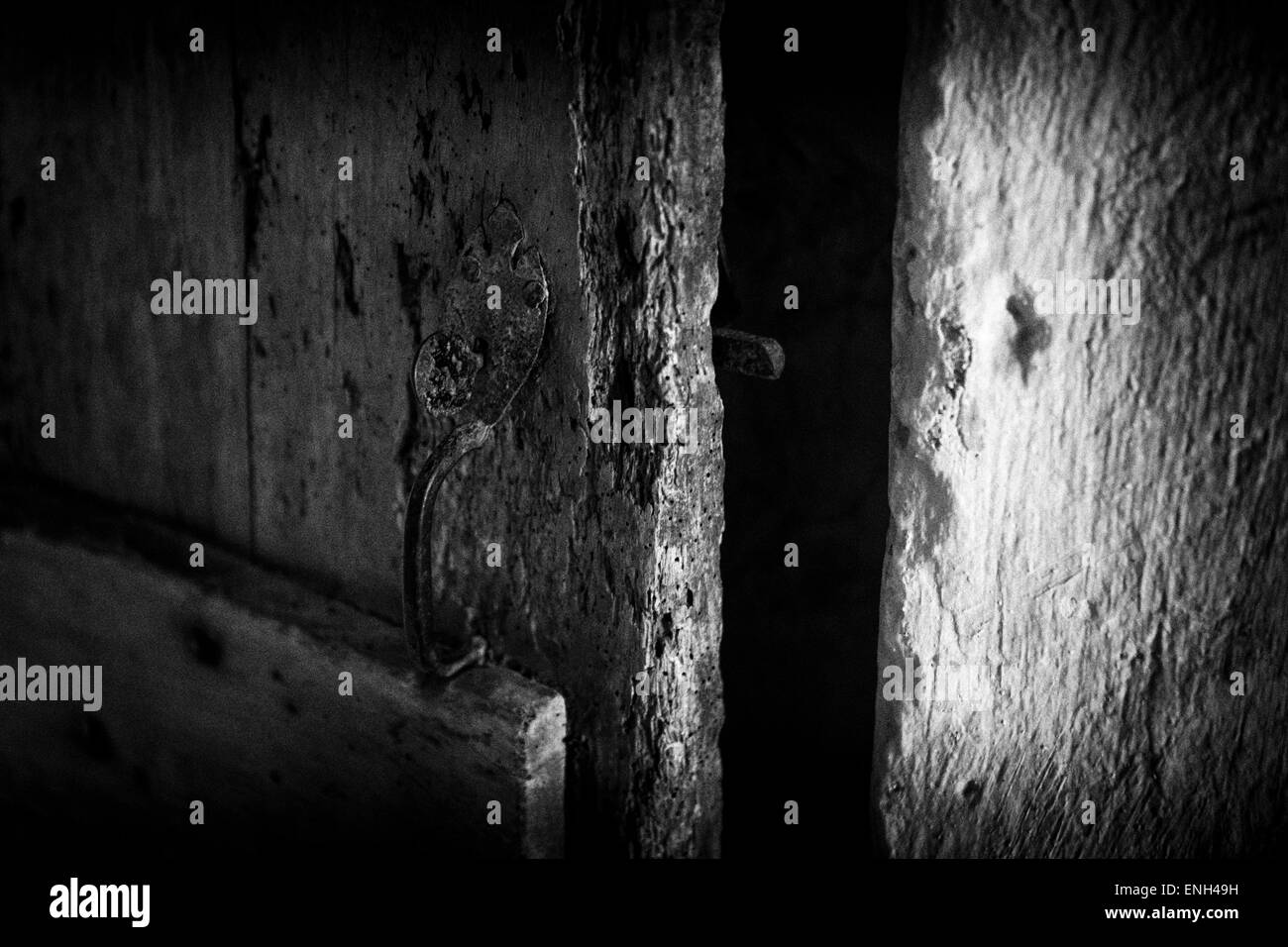Sehr alte mittelalterliche Tür in schwarz und weiß, halb offen, vielleicht ein Geheimnis oder ein Geheimnis hinter zum Ausdruck bringen. Stockfoto