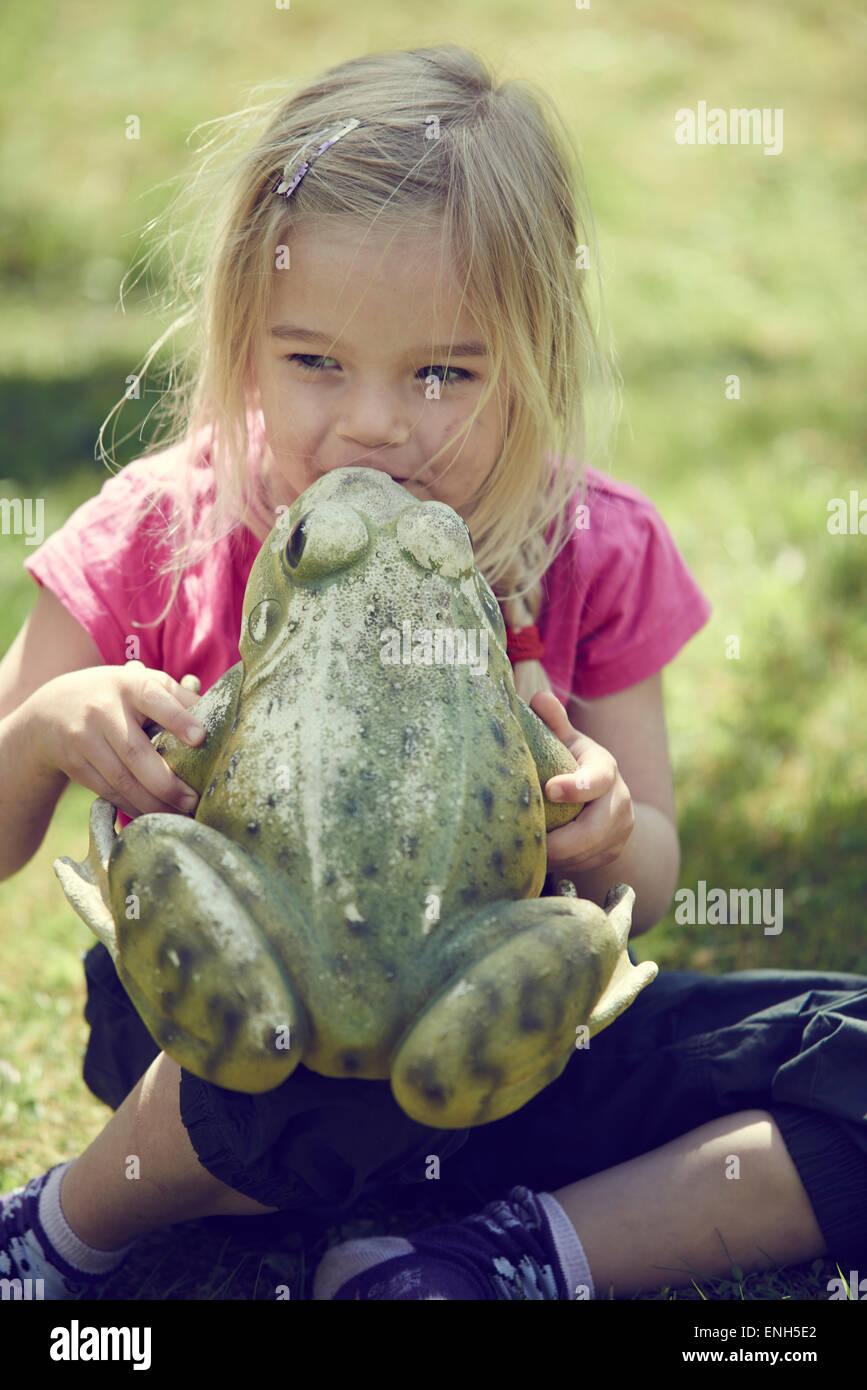 Kleines blondes Mädchen küssen verzaubert Froschkönig Stockfoto