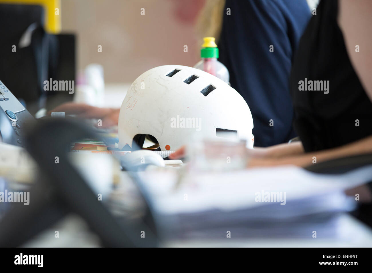 Fahrradhelm auf Schreibtisch im Büro beschäftigt Stockfoto