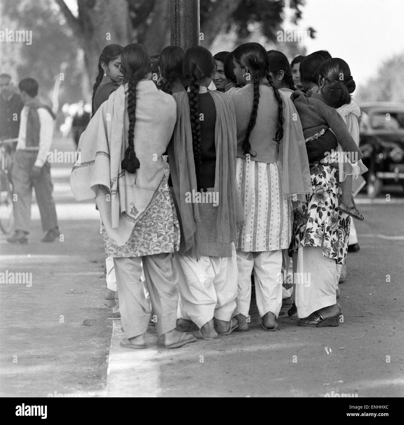 Straßenszenen, New Delhi, Indien, Januar 1961. Gruppe junger Mädchen warten auf Bus von der Seite der Straße. Stockfoto