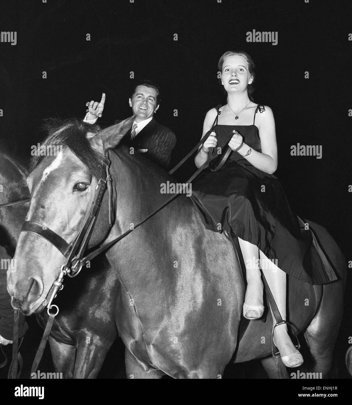 Britischer Musiker Ronnie Ronalde und Braut Corsie auf dem Pferderücken, Teilnahme an einem Rennen um Berkeley Square im Rahmen einer Weihnachtsfeier von Mayfair Club für ein Kinderhilfswerk organisiert. 21. Dezember 1956. Stockfoto