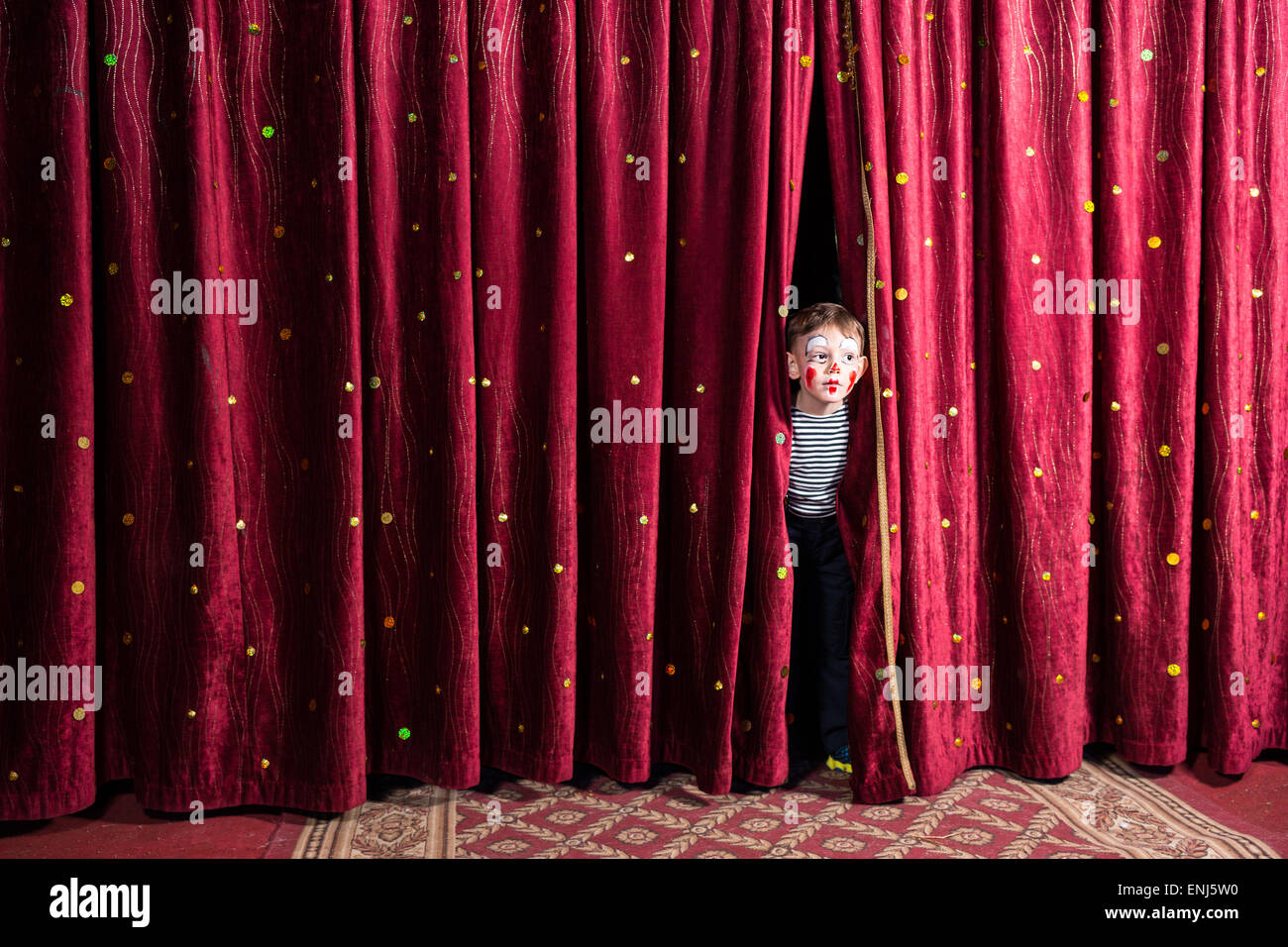 Aufgeregt, kleinen Jungen auf Bühne peering zwischen die Vorhänge in seinem Kostüm und Make-up warten auf die Leistung zu beginnen Stockfoto