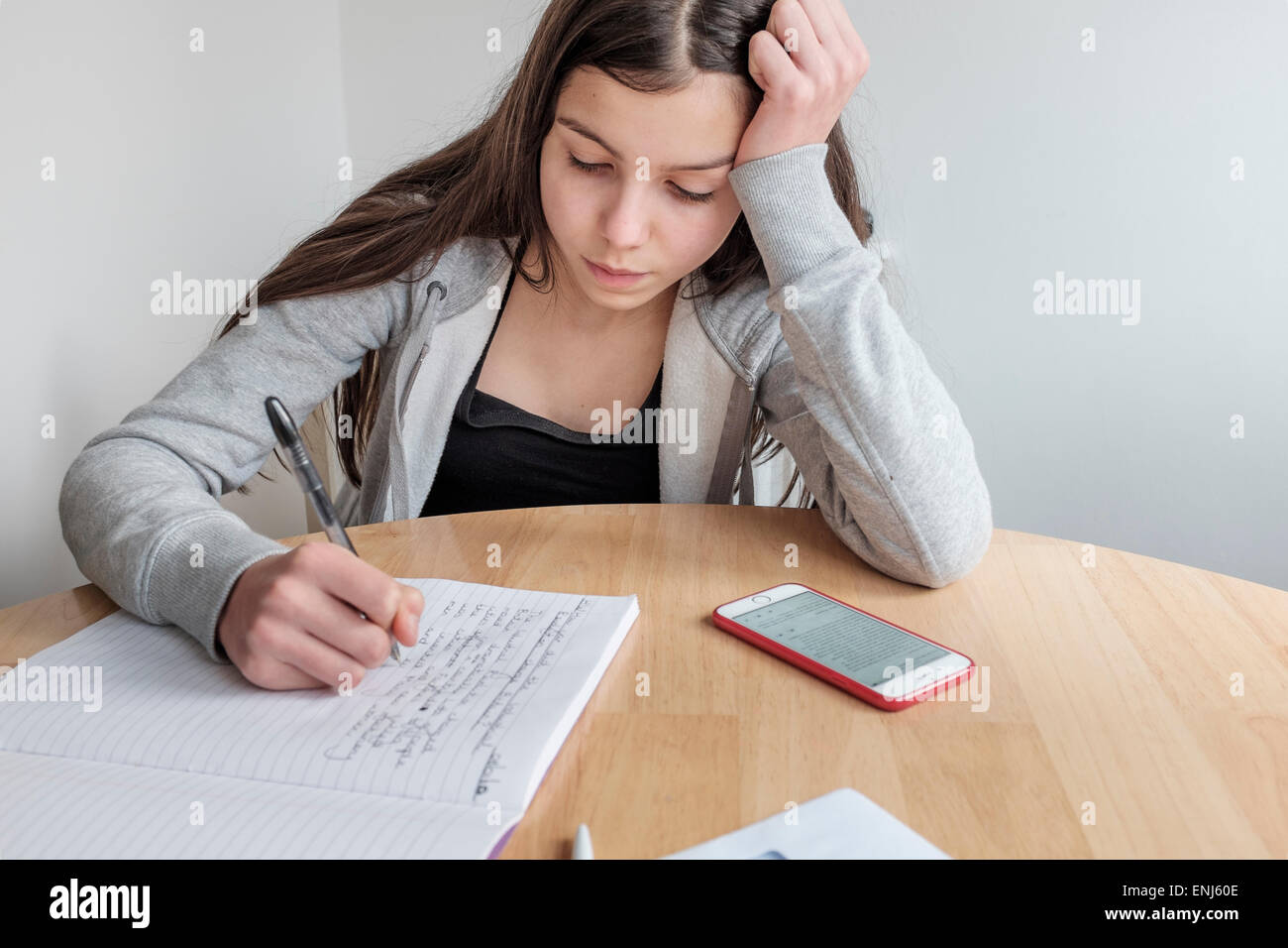 Teenager-Mädchen auf ihre Hausaufgaben, arbeiten mit ihrem Smartphone Stockfoto