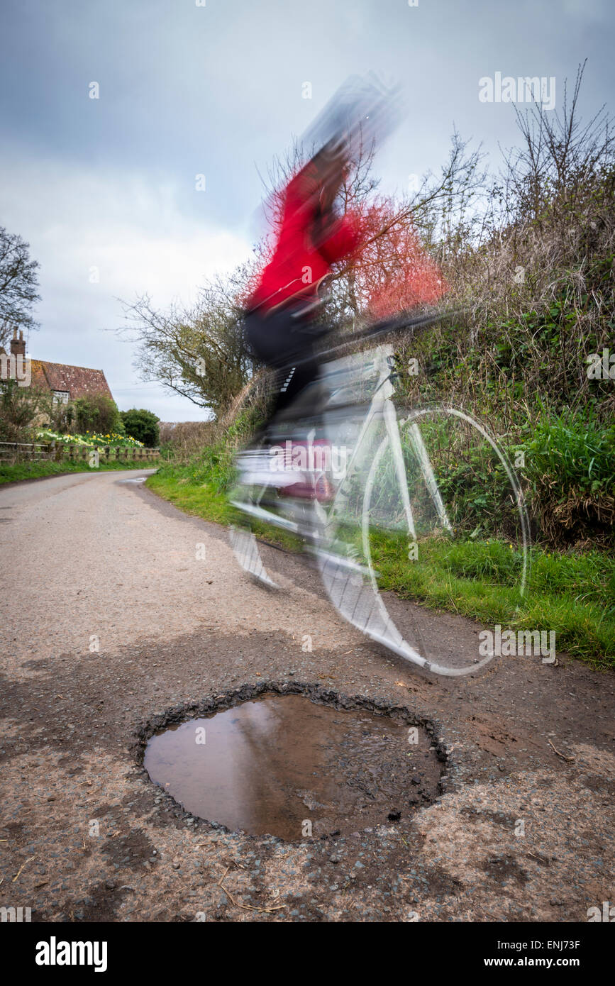 Ein Radfahrer, der Weg durch ein Schlagloch zu verhandeln. Stockfoto