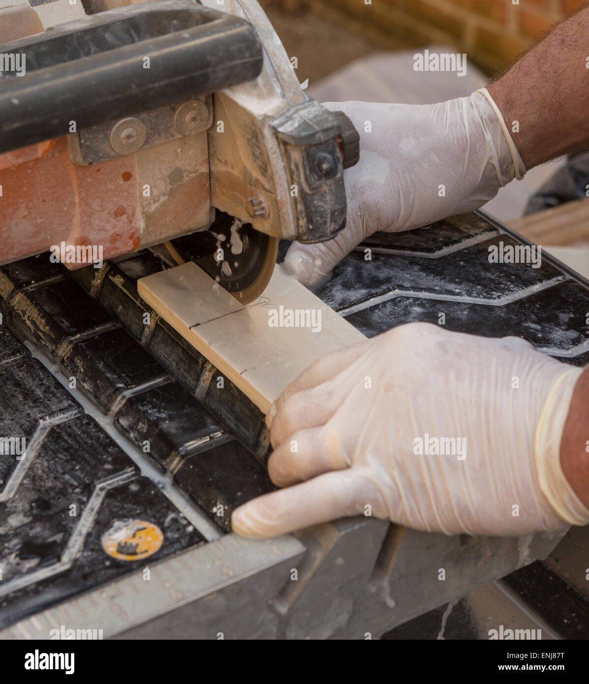 ARLINGTON, VIRGINIA, USA - Arbeiter mit Latex Handschuhen schneidet keramische Fliesen mit einem feuchten Fliesen sah. Stockfoto