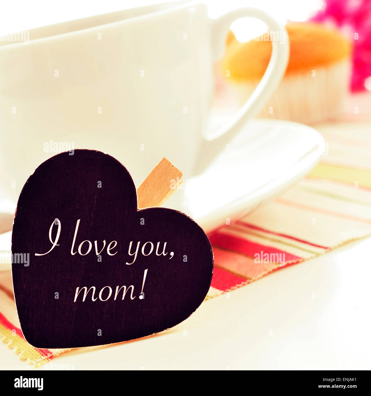 der Satz ich liebe Sie Mama geschrieben in einer Herzform Tafel platziert in einer Tasse Kaffee, mit einigen Muffins im Hintergrund Stockfoto