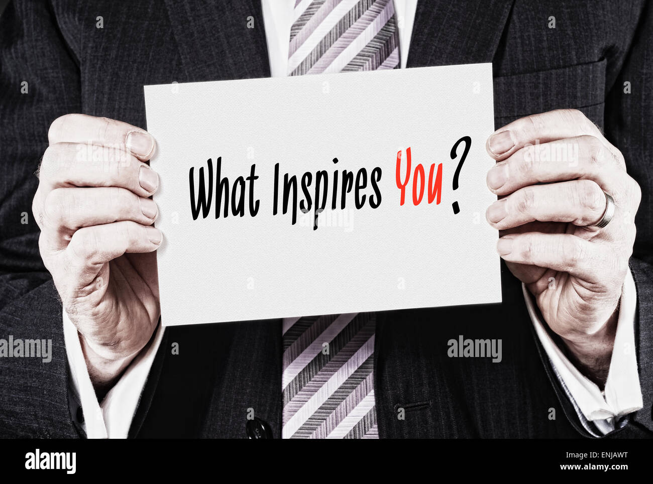 Ein Geschäftsmann hielt eine Karte mit den Worten, was inspiriert dich? Stockfoto