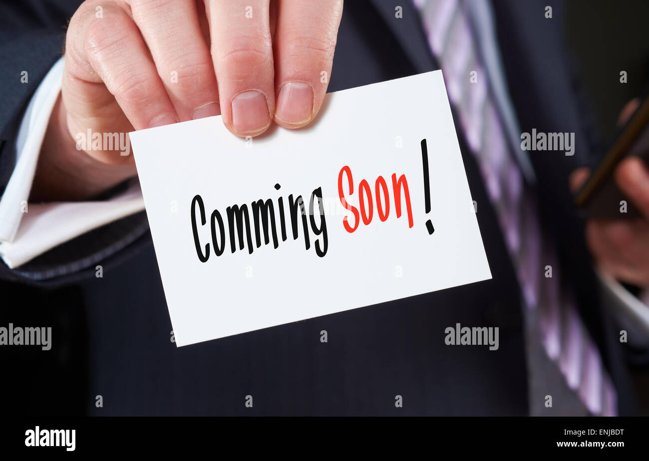 Ein Geschäftsmann hält eine Visitenkarte mit den Worten: Coming Soon, darauf geschrieben. Stockfoto