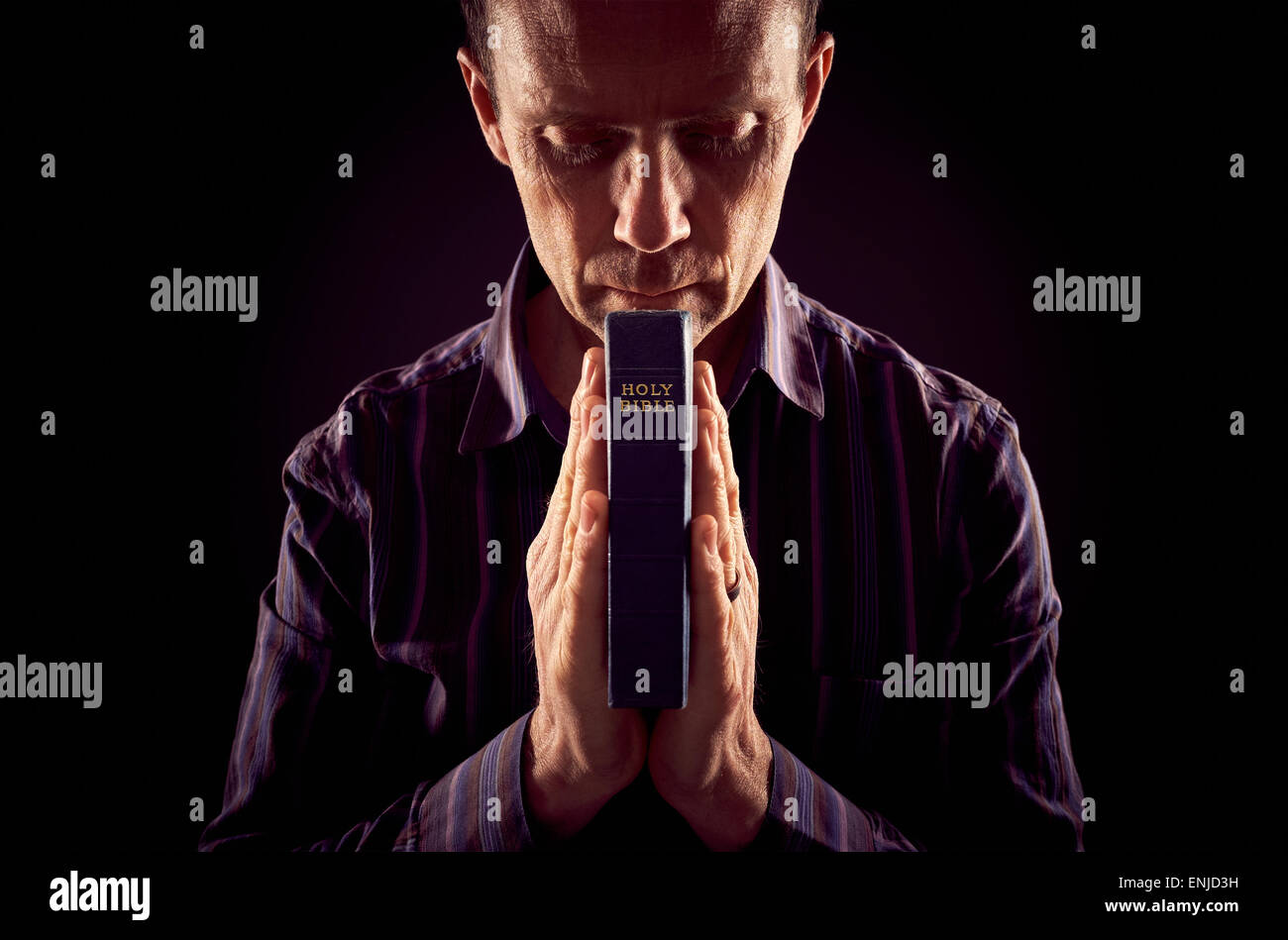 Vorderansicht eines Mannes beten im Dunkeln mit Licht auf beiden Seiten von ihm. Stockfoto