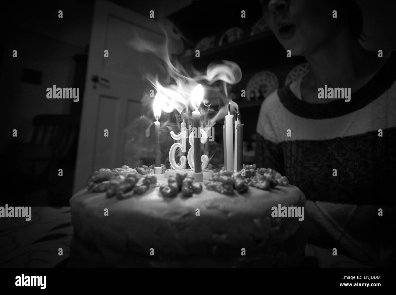 Eine Frau Ausblasen der Kerzen auf ihrem Geburtstagskuchen. Instagram Typ Styling angewendet einige leichte Korn hinzugefügt. Stockfoto