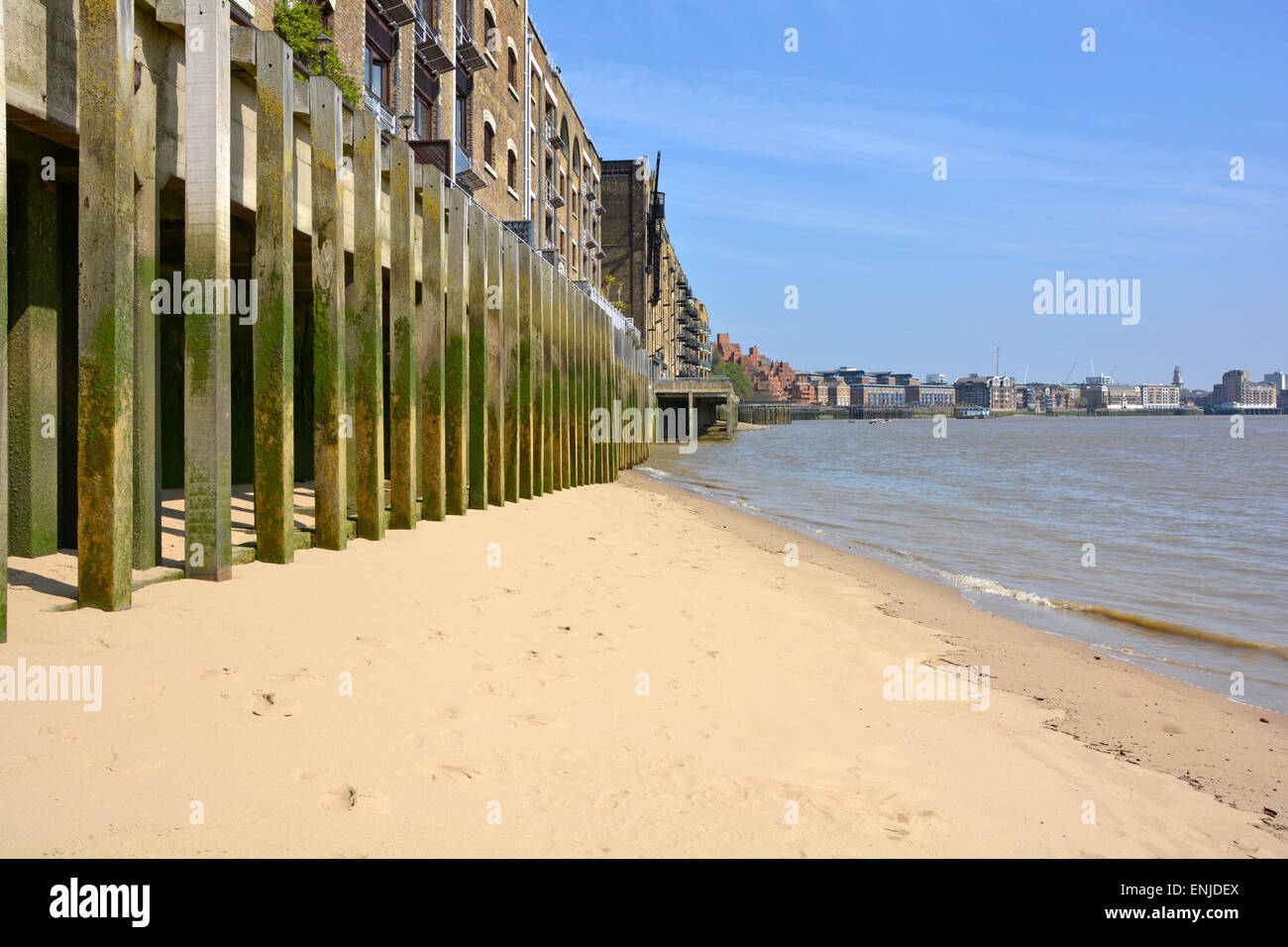 Sauberer fester Strandabschnitt am Ufer der Themse unter dem alten Lagergebäude am Flussufer auf Holzpfählen in den Wapping Tower Hamlets East London, Großbritannien Stockfoto