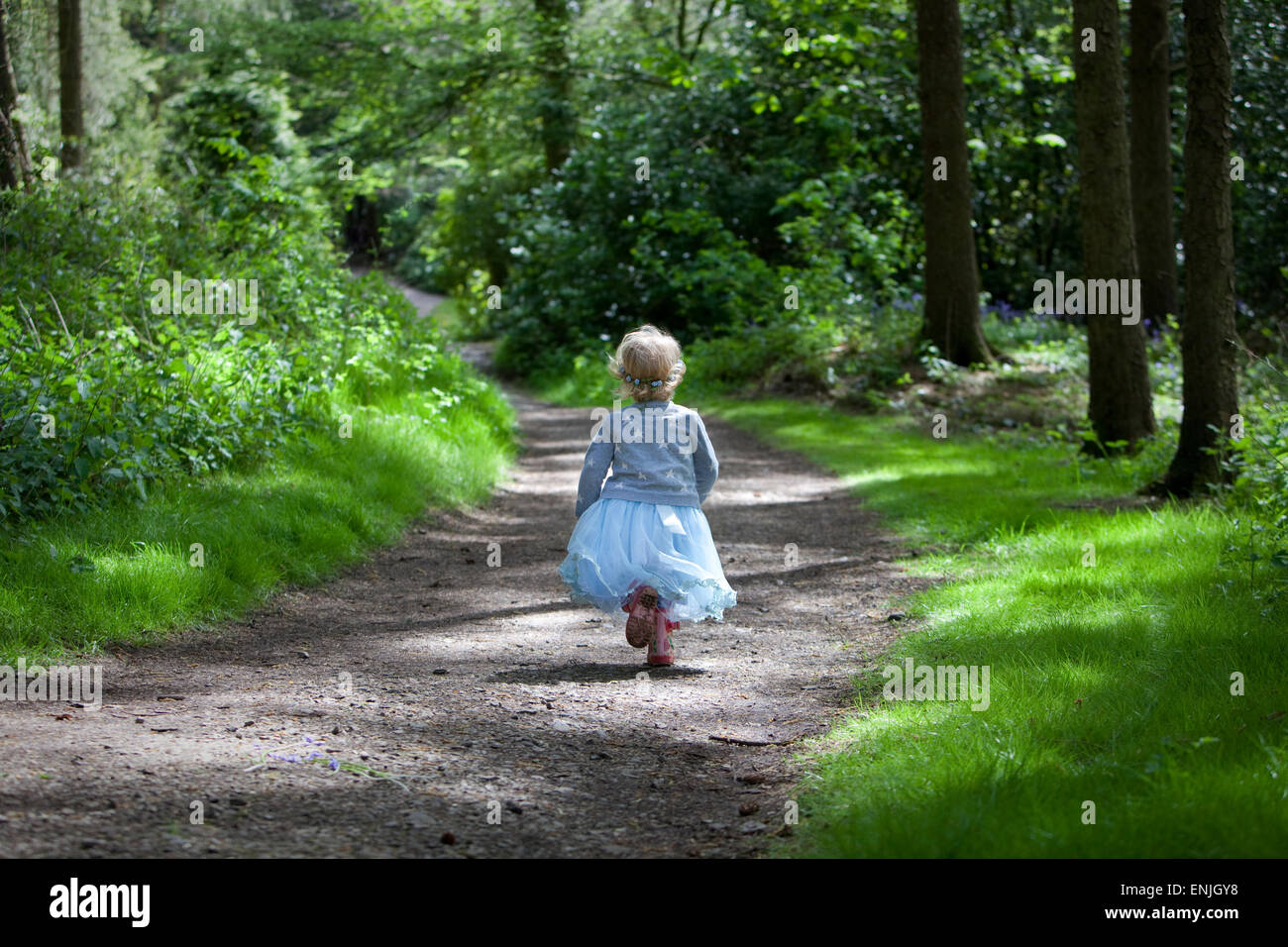 Kleines Mädchen im blauen Kleid, die durch den Wald laufen. Stockfoto
