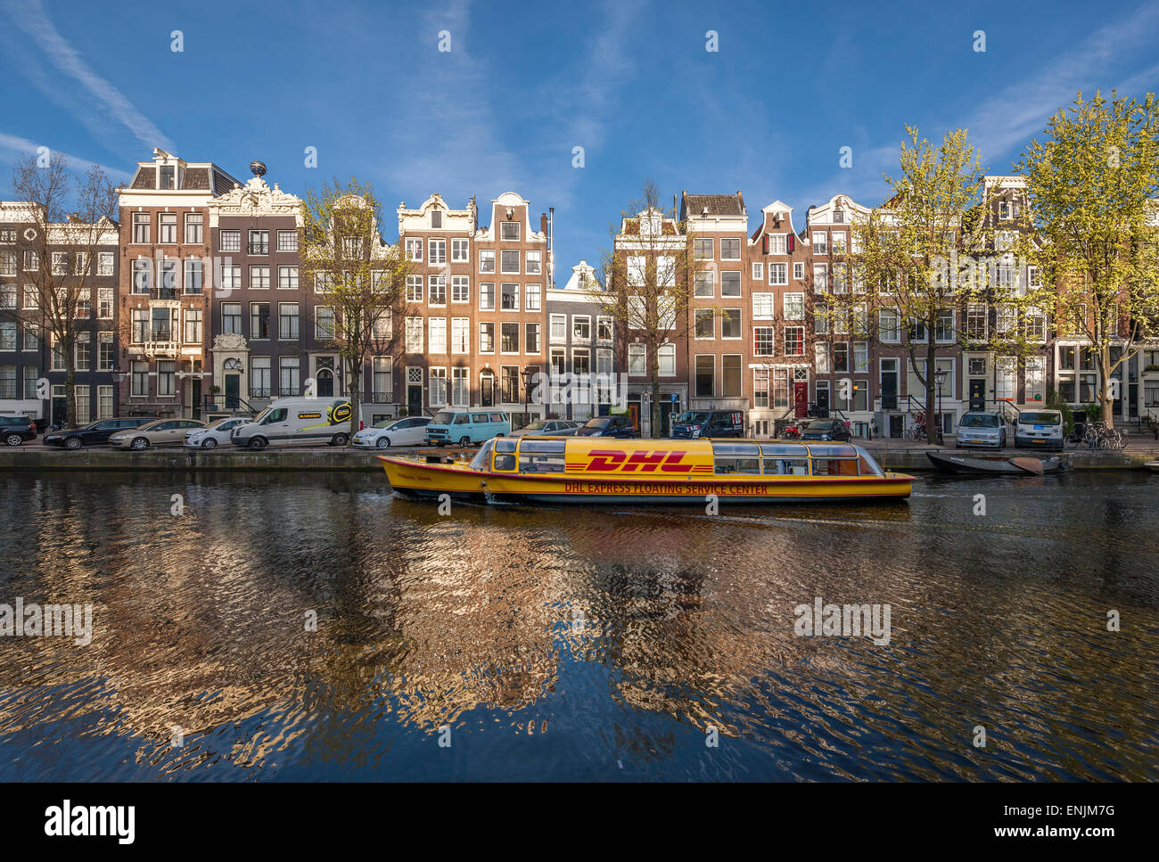 Amsterdam Singel Gracht mit DHL Lieferung Kanalboot im frühen Morgen um 07:00 im Frühjahr. Stockfoto