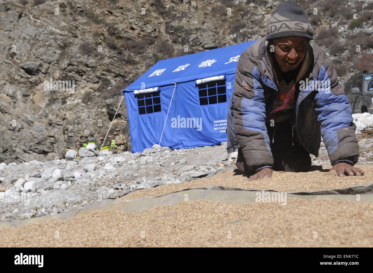 Tingri, China Tibet autonome Region. 4. Mai 2015. Ein Mann trocknet Highland Gerste in der Sonne auf eine vorübergehende Unterkunft in Rongxia Township in Tingri, Südwest-China Tibet autonome Region, 4. Mai 2015. Mehr als 800 Menschen in Rongxia haben gut mit sicheren Lebensmitteln und Trinkwasser untergebracht worden. Die Region wurde schwer getroffen und von April 25 Erdbeben in Nepal. © Norbu Cering/Xinhua/Alamy Live-Nachrichten Stockfoto