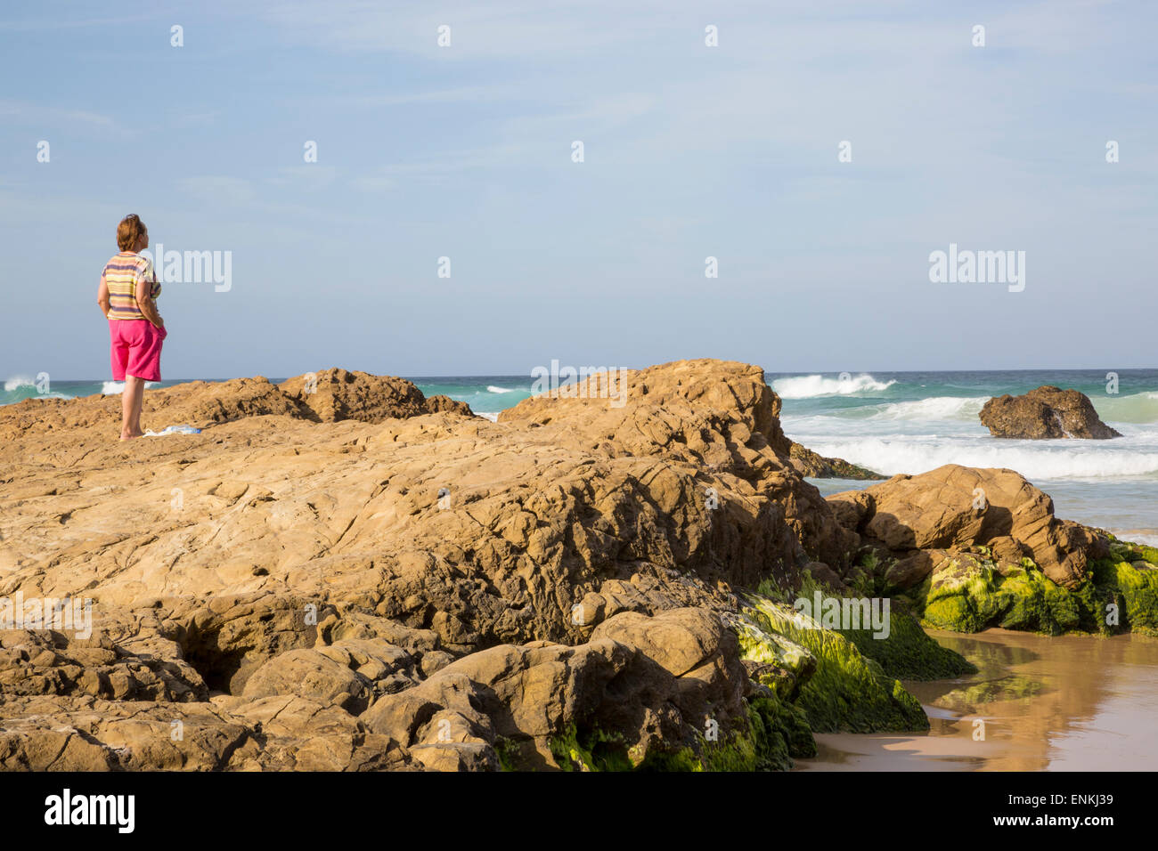 Einsame Frau am felsigen Strand Stockfoto