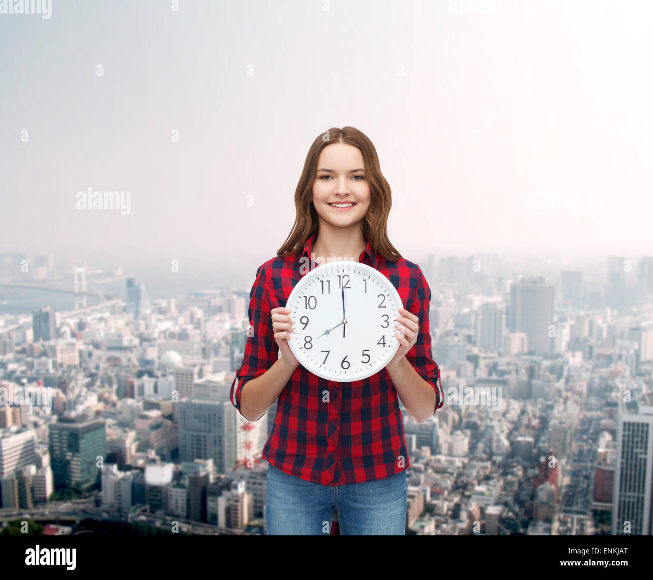 junge Frau in Freizeitkleidung mit Wanduhr Stockfoto