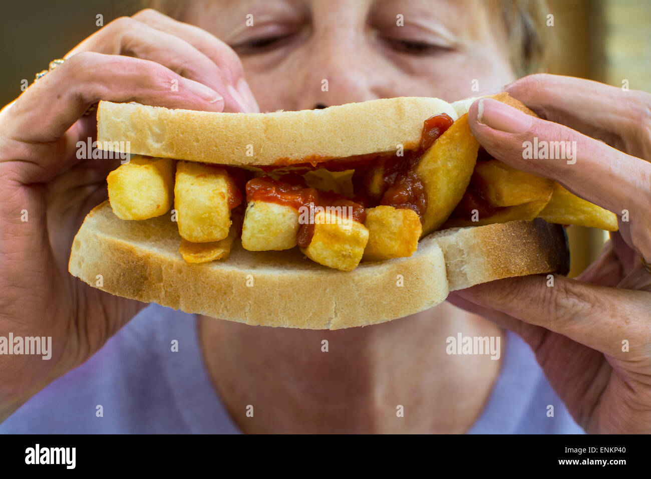 Eine Kartoffel-Chips-Sandwich, allgemein bekannt als ein Chip butty im Vereinigten Königreich, von einer Frau gefressen Stockfoto