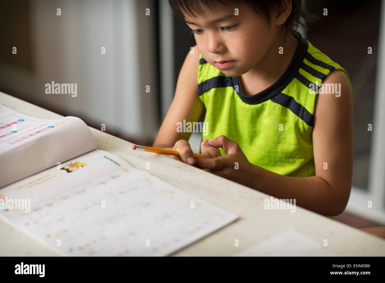 Ein japanischer junge studiert Japanische Hausaufgaben in der Küche. Stockfoto