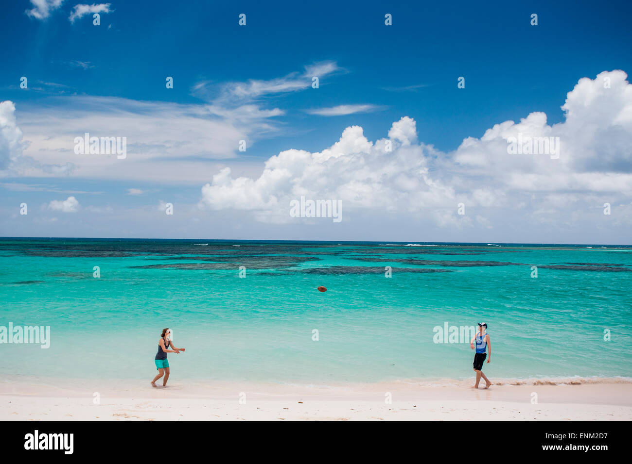 KUH WRECK BEACH RESORT, BRITISCHE JUNGFERNINSELN, KARIBIK. Ein Mann und eine Frau werfen einen Fußball auf einem weißen Sandstrand mit Türkis Meer hinter. Stockfoto