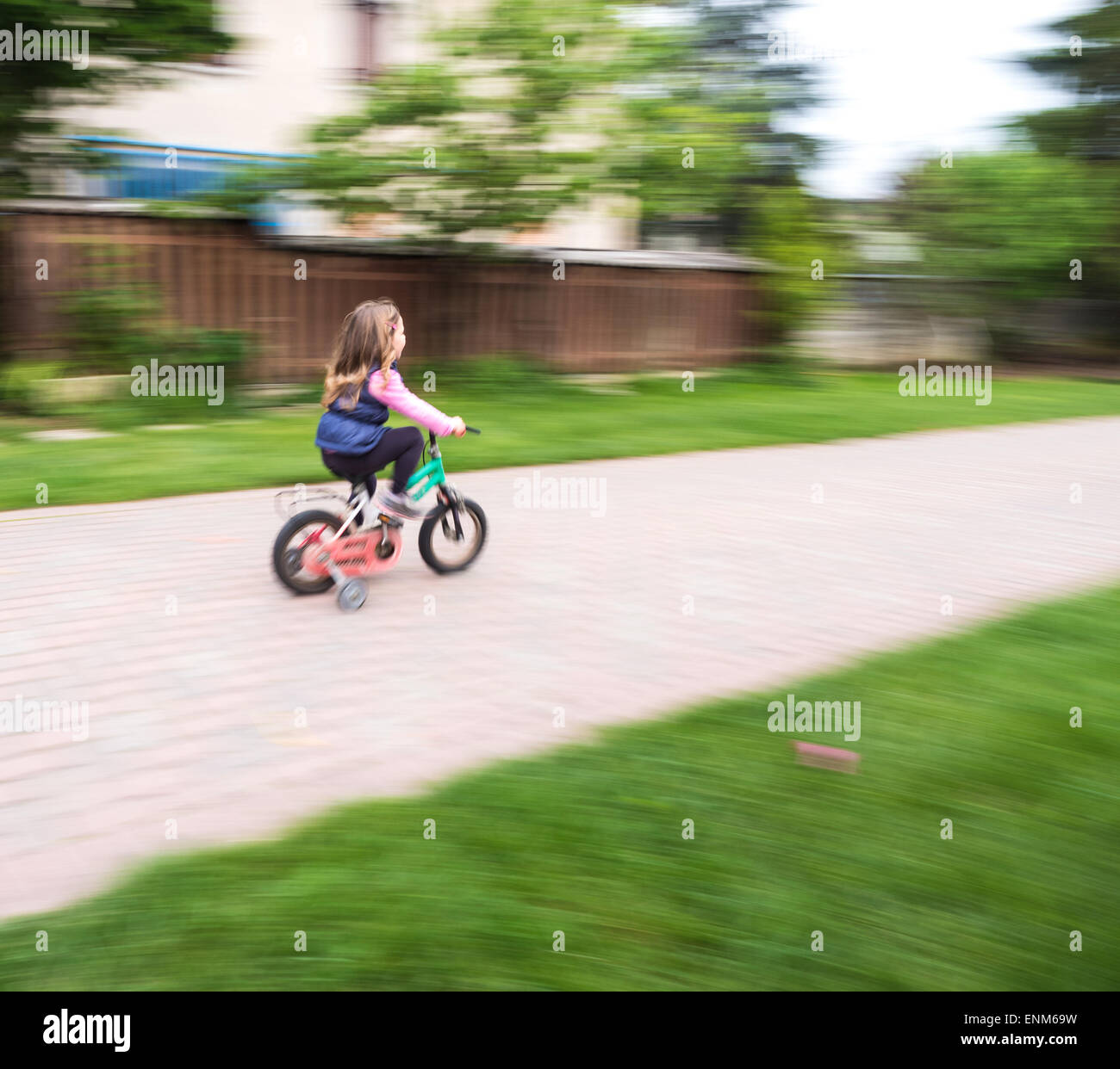 kleines Mädchen Fahrt schnell mit Fahrrad mit Rollen Stockfoto