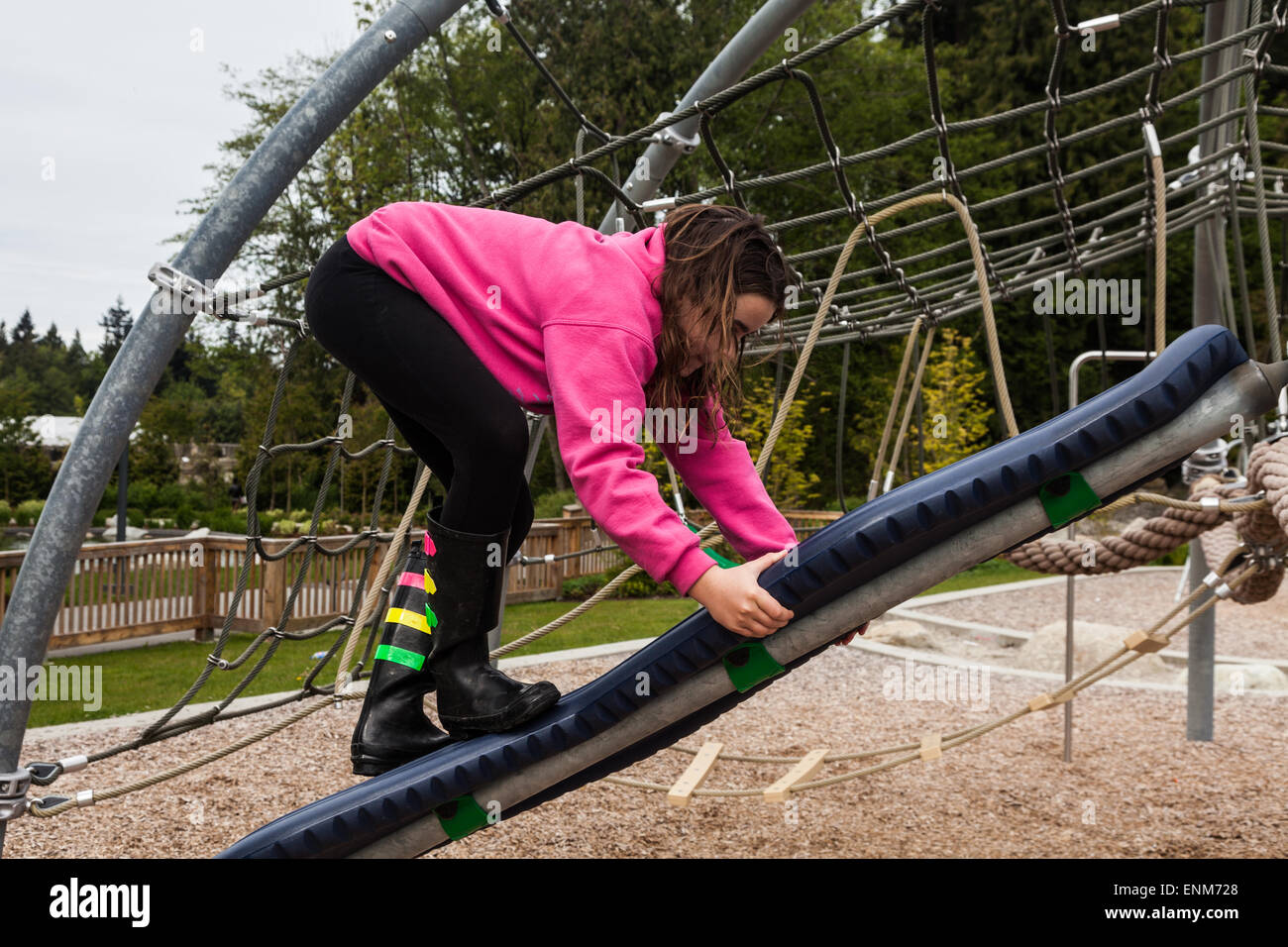 Junges Mädchen Klettern auf einem schwenkbaren Brett auf einem Kinderspielplatz Stockfoto