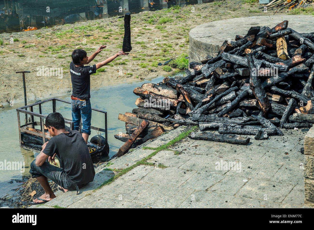 Kinderarbeit - verbrannten Kinder sortieren Protokolle nach einer Feuerbestattung in Pashupatinath Tempel in Kathmandu Stockfoto