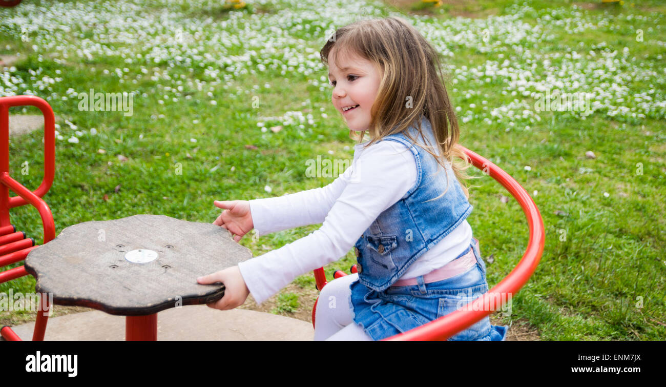 kleines Mädchen verwandelt sich in eine manuelle Karussell in einen Spielplatz im freien Stockfoto