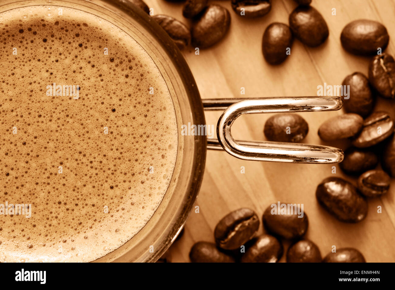 Nahaufnahme von einer Tasse Kaffee und einige Kaffeebohnen auf einem Holztisch in Sepia Tönung Stockfoto