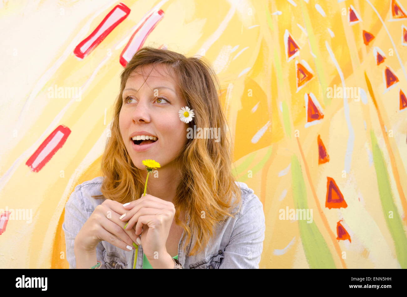 Brünette Mädchen posiert eine bunte Kulisse mit Gänseblümchen Stockfoto