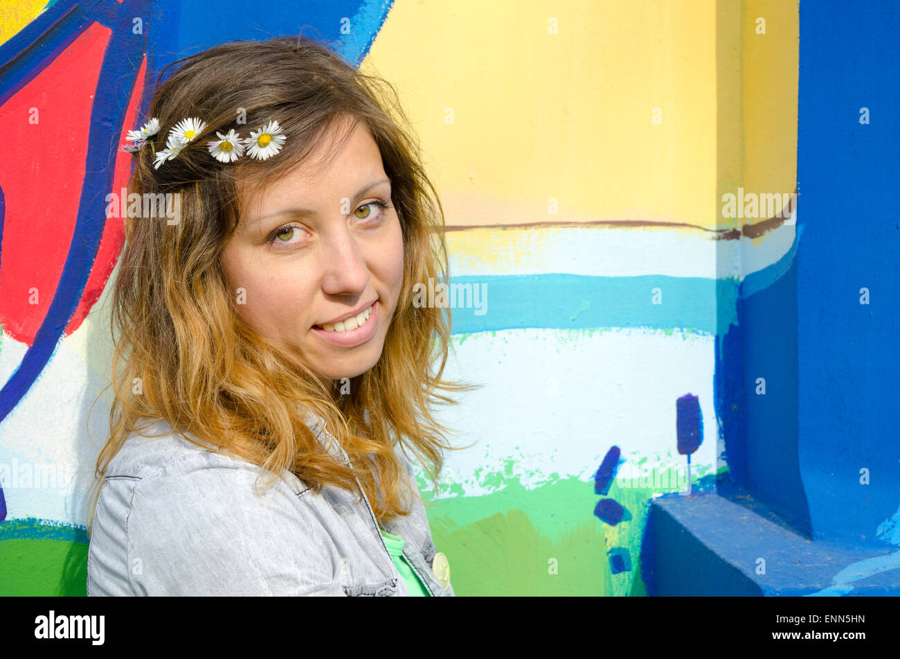 Brünette Mädchen posiert eine bunte Kulisse mit Gänseblümchen Stockfoto