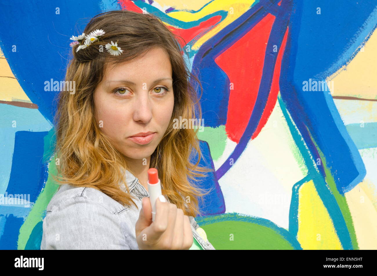 Brünette Mädchen posiert vor dem farbenfrohen Hintergrund hält Lippenstift Stockfoto