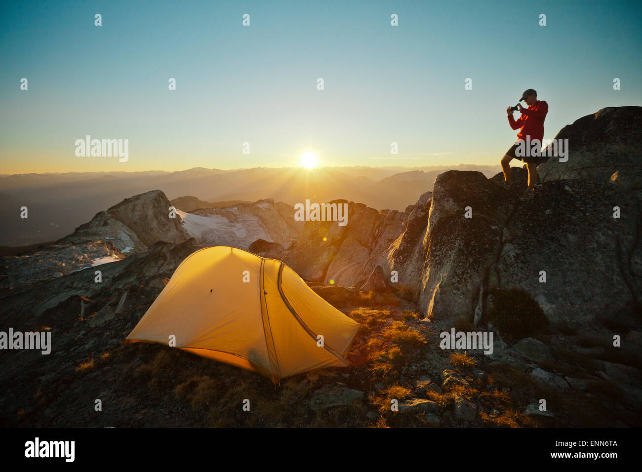 Ein Wanderer nimmt ein Bild von seinem Zelt beim camping auf Steinbrech Peak. Stockfoto