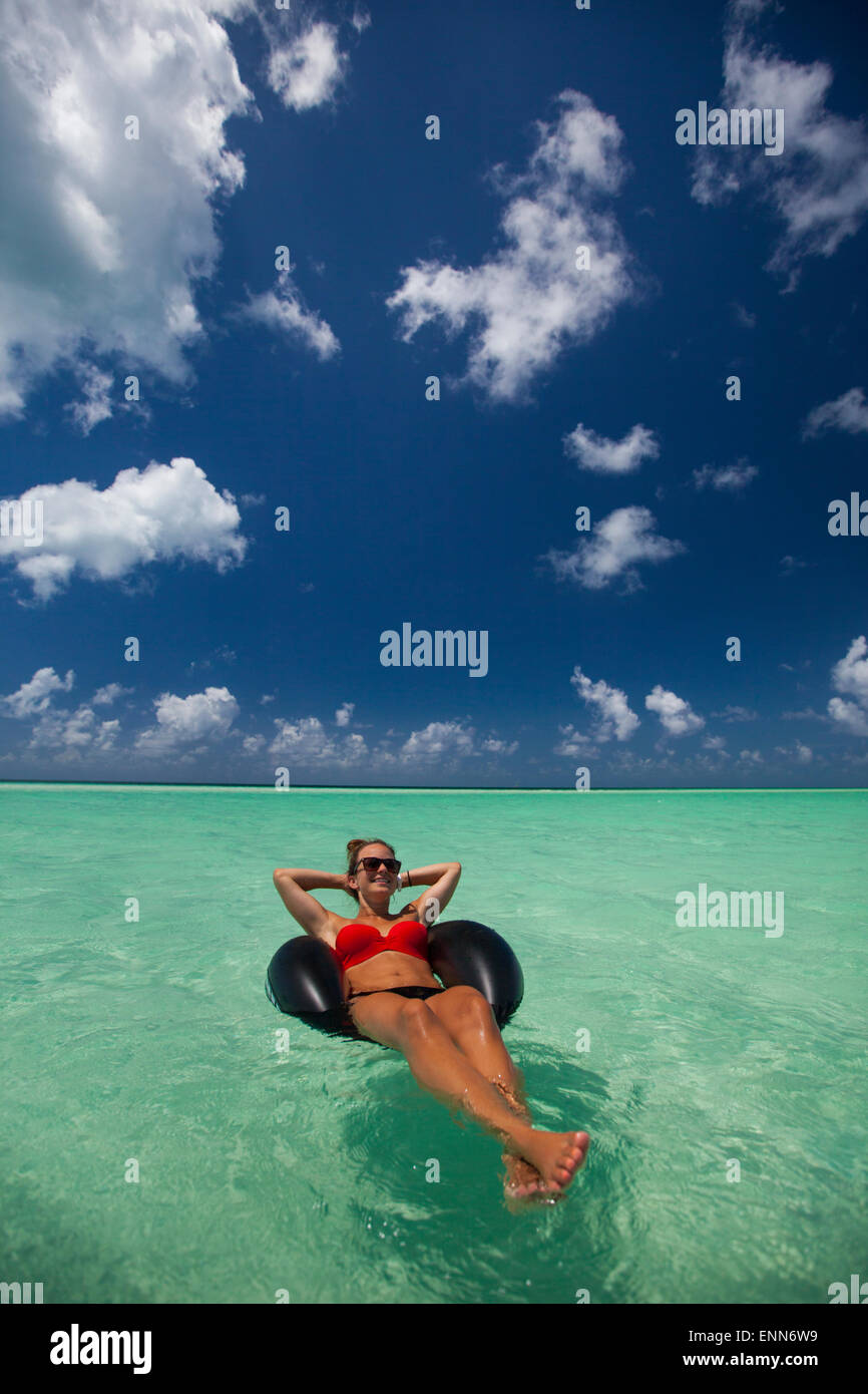 Eine junge Frau entspannt auf einem aufblasbaren Reifen im türkisfarbenen Wasser während des Urlaubs in Cayo Coco, Kuba. Stockfoto