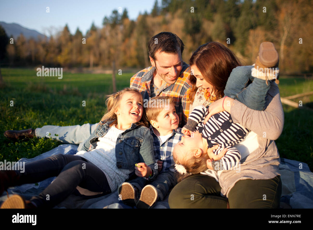 Eine Familie von fünf lachen zusammen sitzend auf einer Decke. Stockfoto