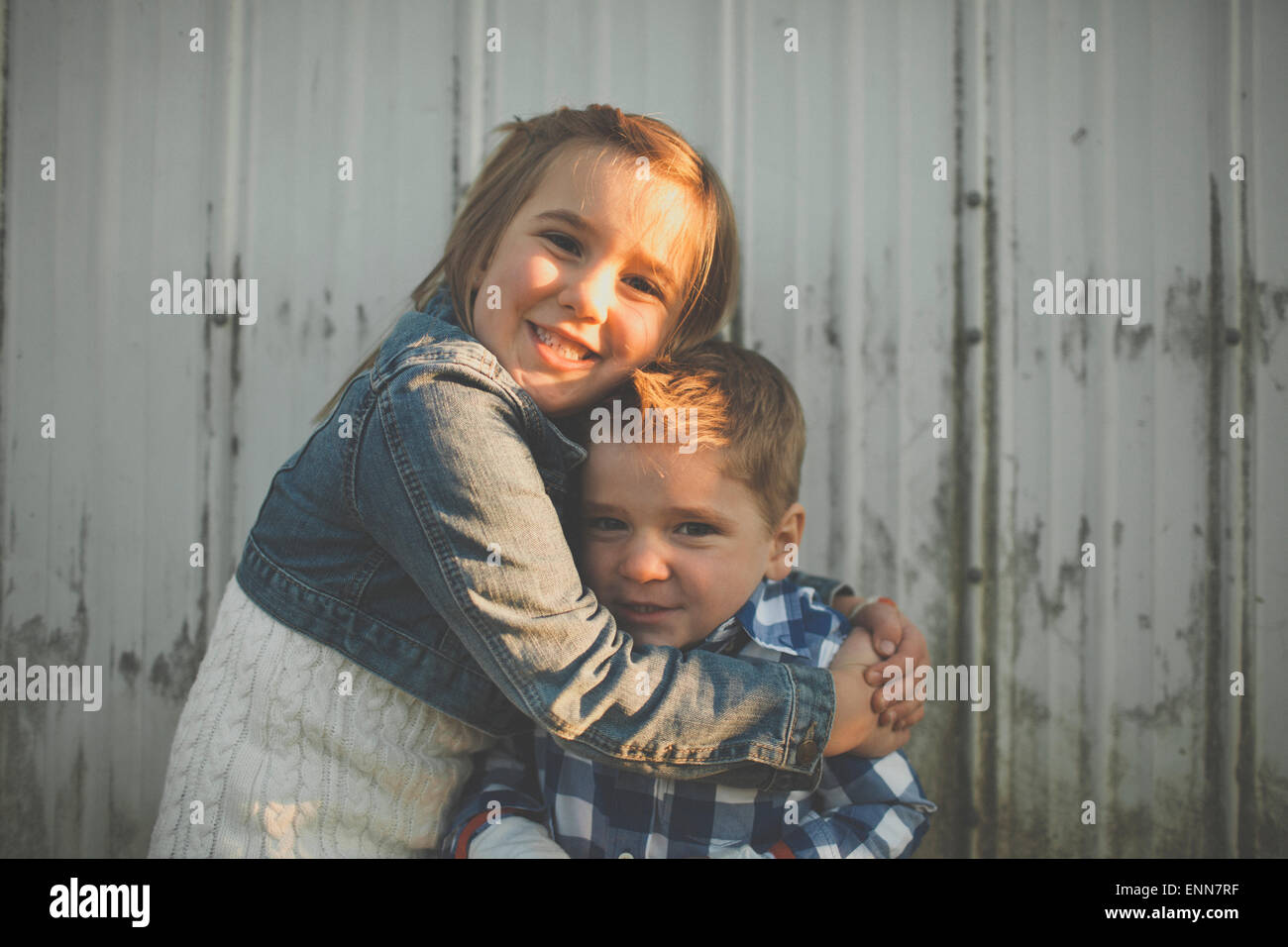 Ein junges Mädchen gibt ihr jüngeren Bruder eine Umarmung. Stockfoto