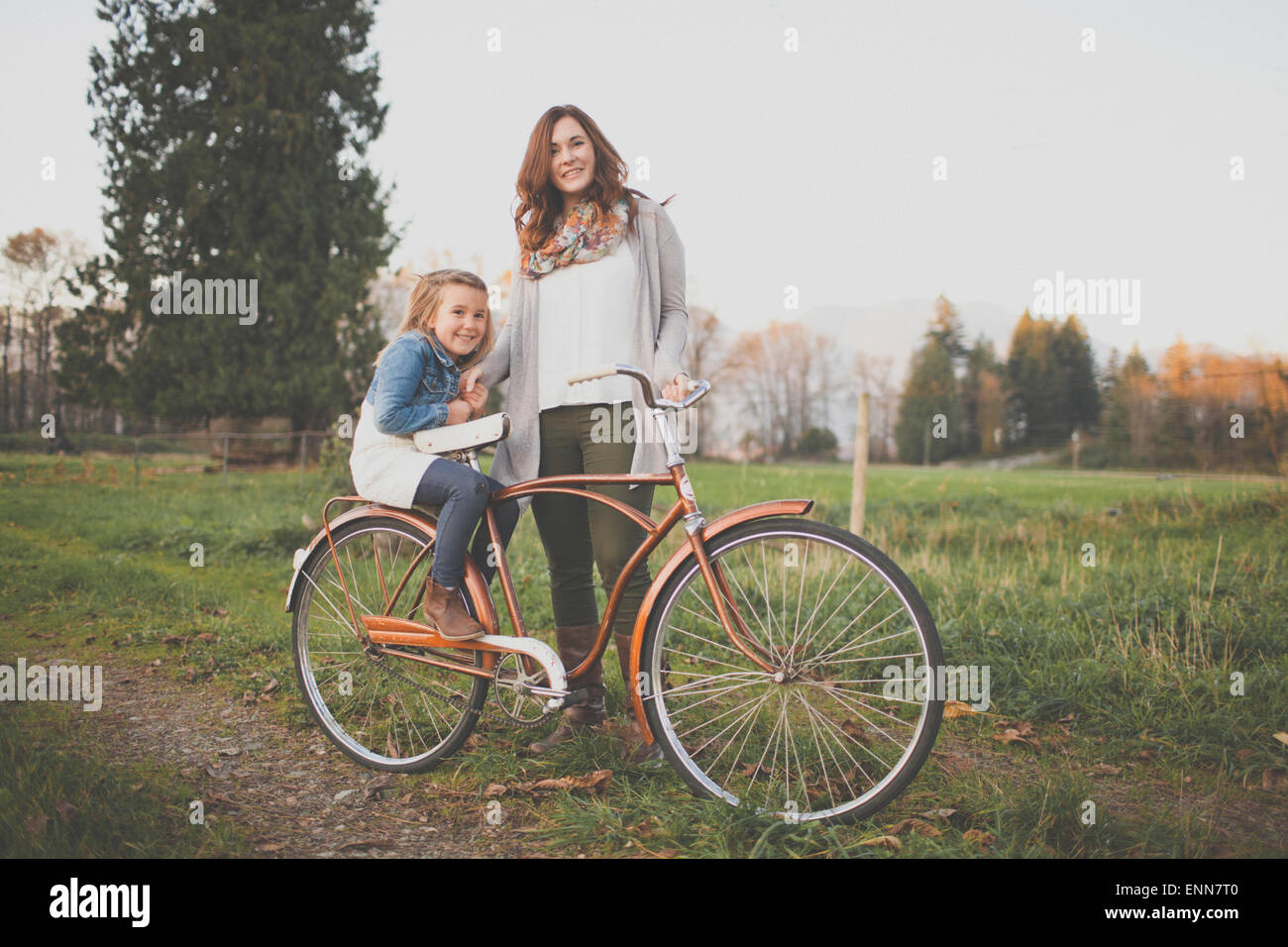 Eine Mutter und Tochter posieren mit einem altmodischen Fahrrad. Stockfoto