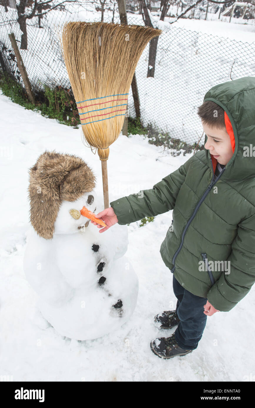 Schneemann mit Kind auf dem Hof. Winter Stockfoto