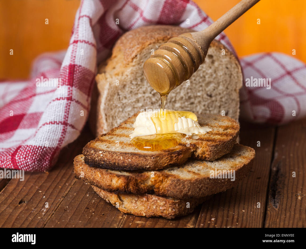 Geröstetes Brot mit Honig und Honig-Wagen auf einem hölzernen Hintergrund. Stockfoto