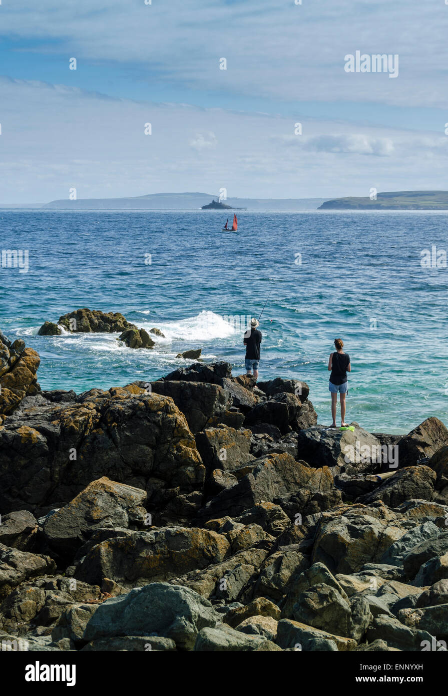 Ein paar Blick über das Meer in St Ives Bay, Cornwall. Ein Segelboot auf dem Horizont und Godrevy Leuchtturm in der Ferne. Stockfoto