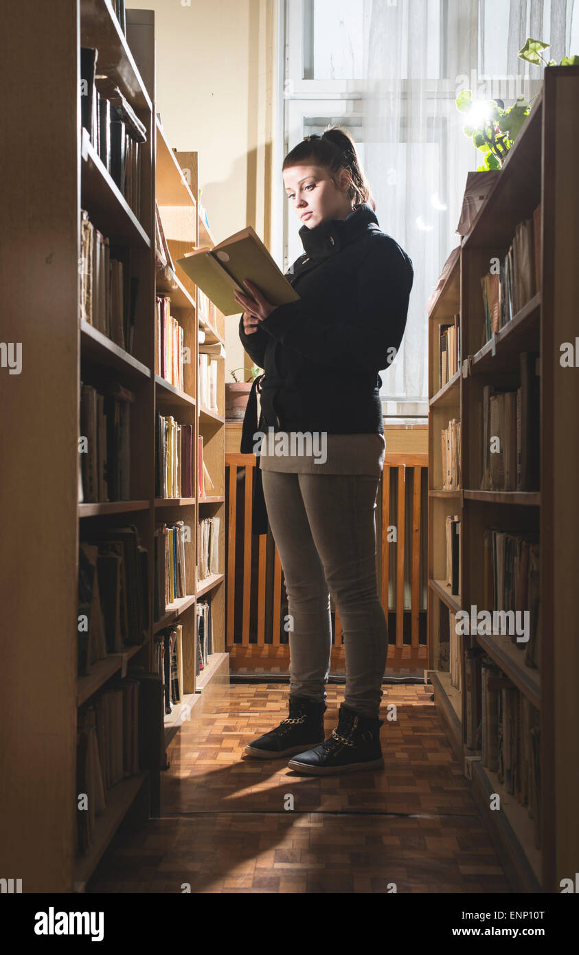 Studentin in einer Bibliothek. Blick auf Buch Stockfoto