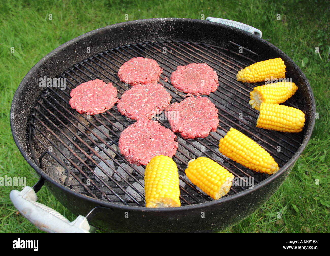 Barbecue-Grill mit Beef-Burger und Maiskolben Stockfoto