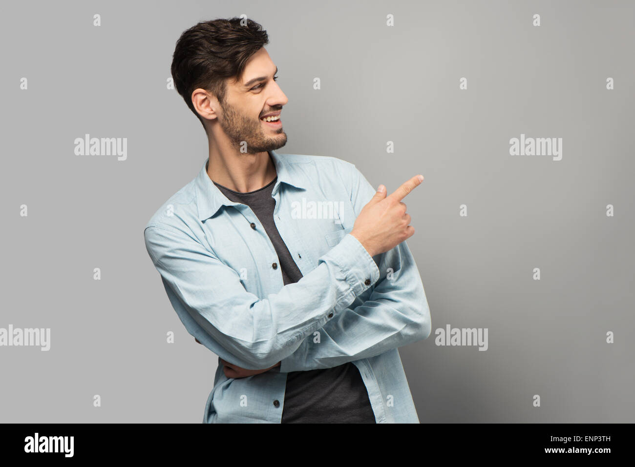 Lächelnder junge Mann zeigt auf etwas Stockfoto