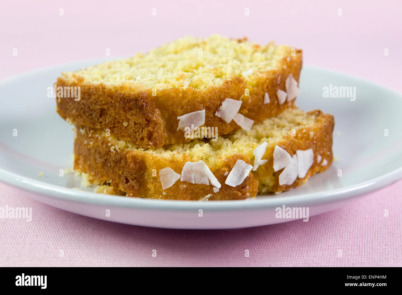 In Scheiben geschnitten hausgemachter Kokos-Kuchen auf Teller vor einem rosa Hintergrund Stockfoto