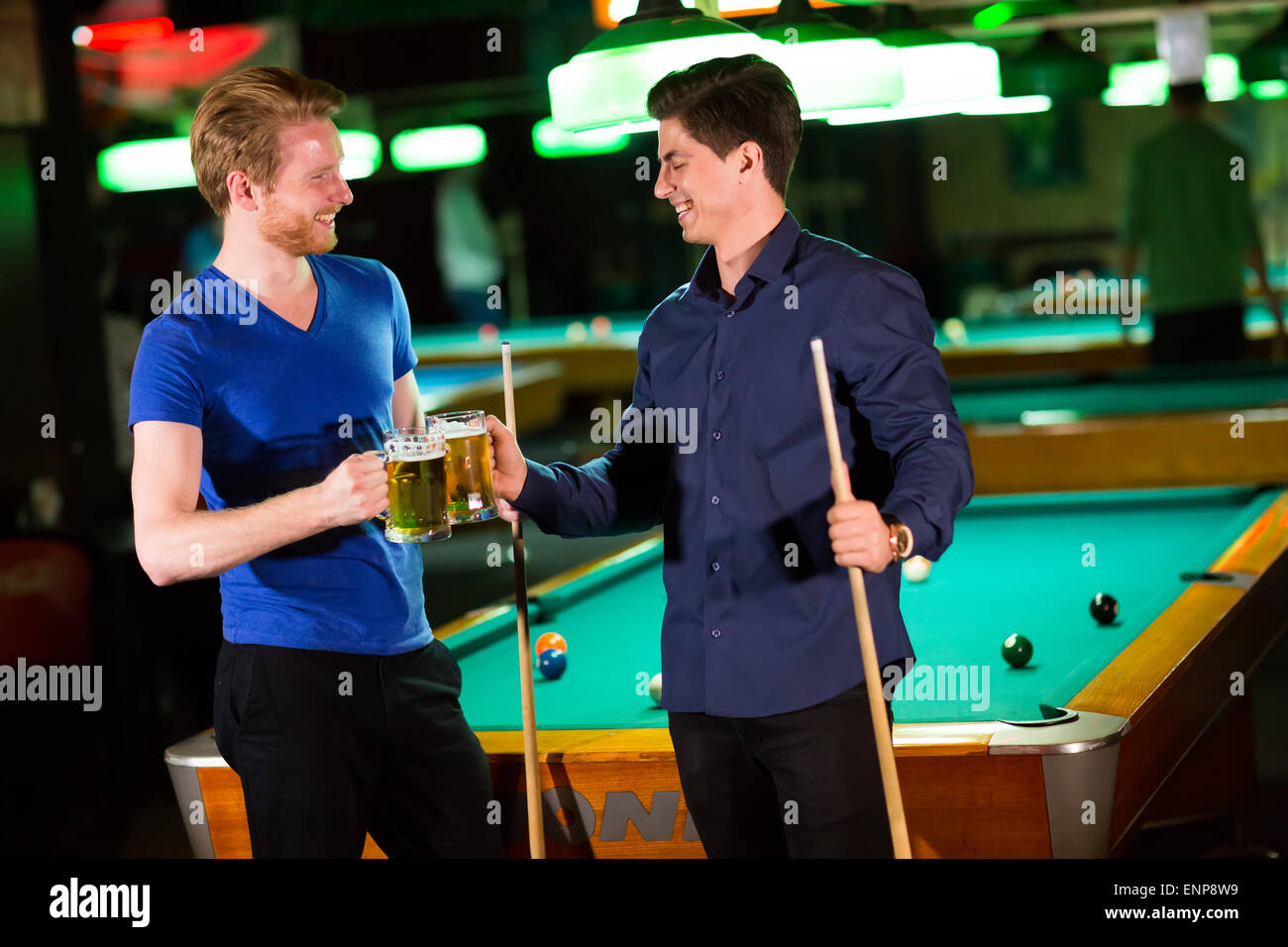 Junge Männer, Billard spielen und Bier trinken Stockfoto