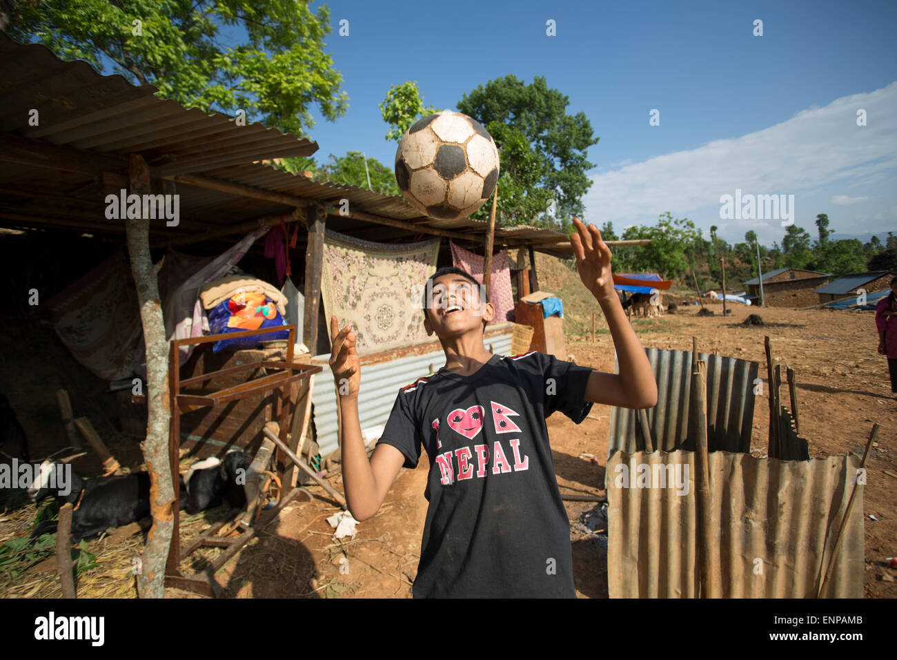 Eine junge Überlebende des Erdbebens 2015 spielt mit einem Fußball außerhalb seiner Familie temporäre Hütte nach der Zerstörung ihrer Heimat. Stockfoto